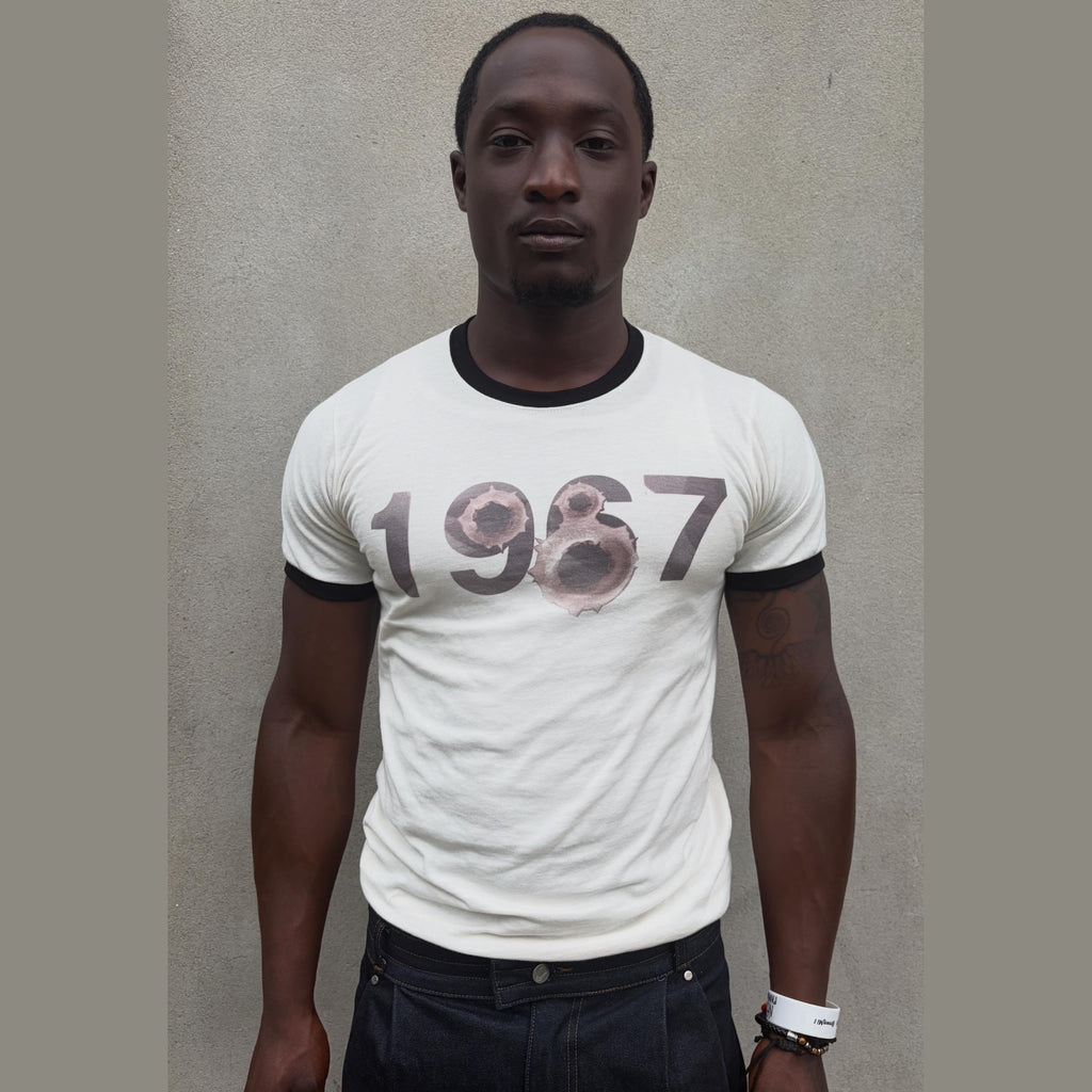White 1967 TEE ringer tee with distressed bullet hole graphic on model