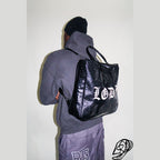 Black glossy crocodile 3-in-1 utility bag worn as backpack with white Gothic lettering